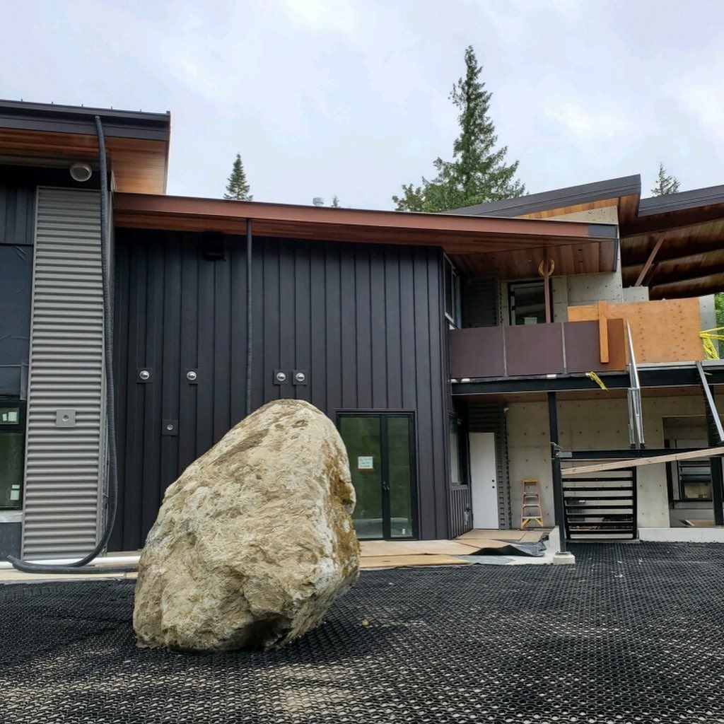 A large rock is sitting in front of a house under construction