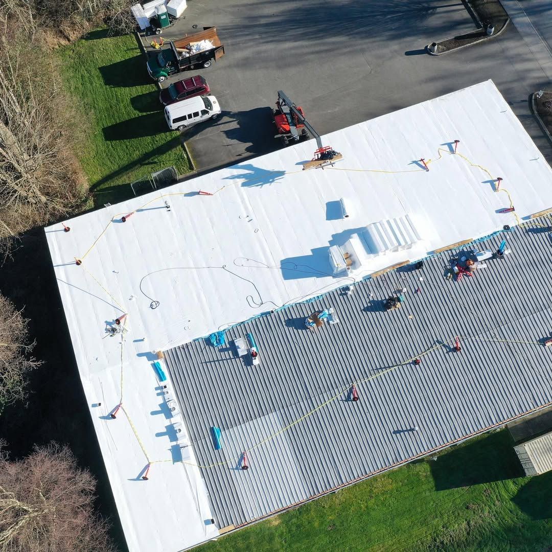 An aerial view of a building with a white roof being installed.