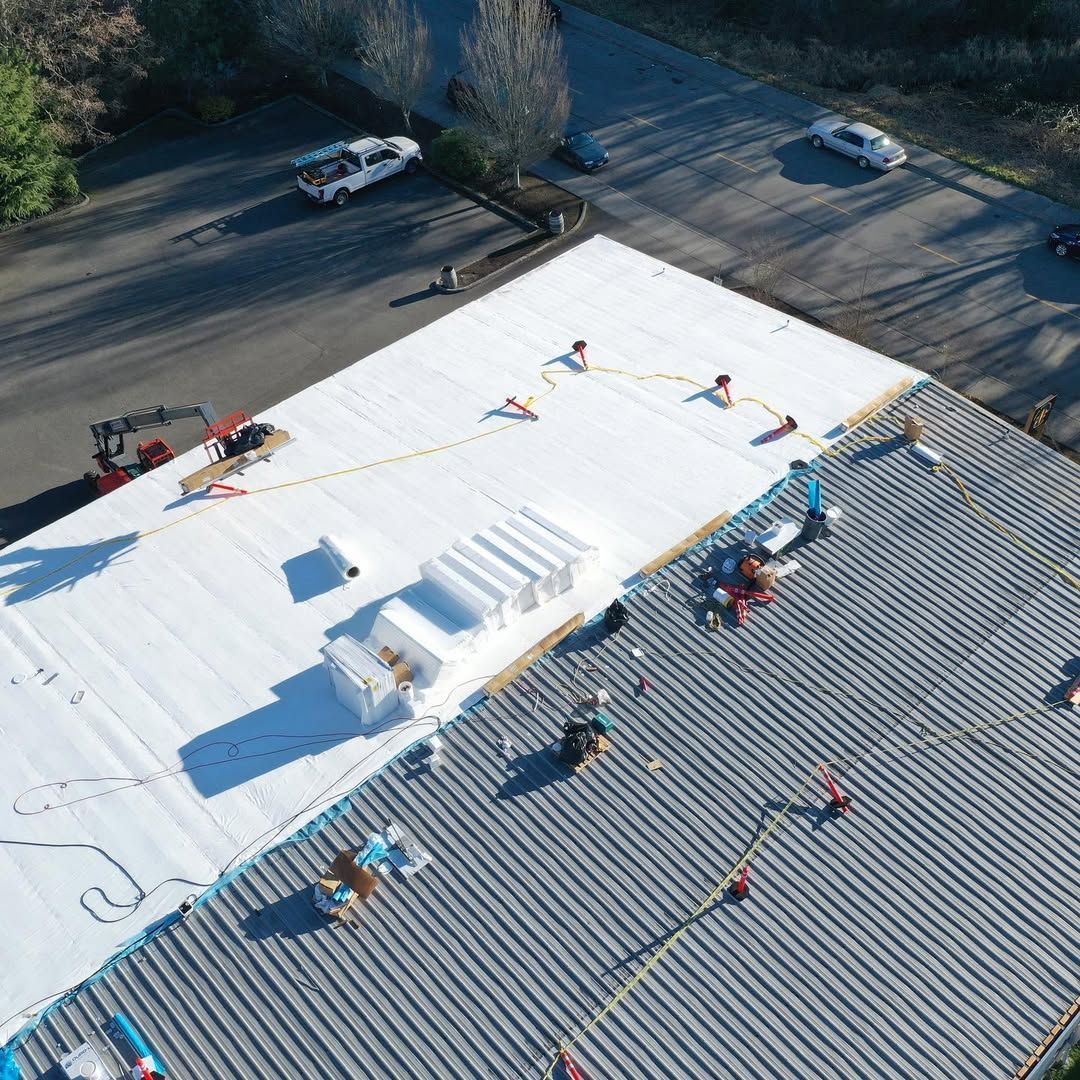 An aerial view of a white roof being installed on a building.