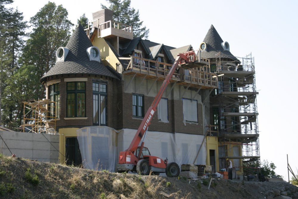 A large house is being built with a red crane in front of it