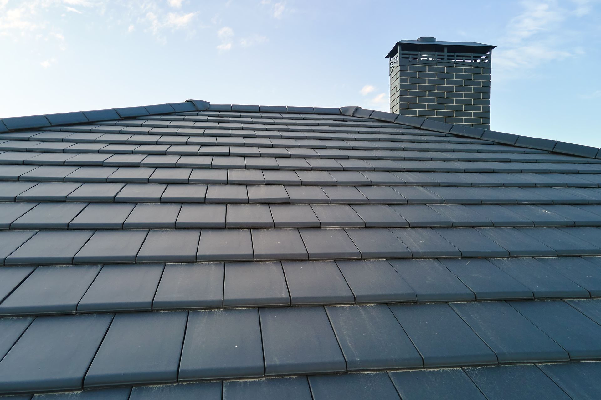 A roof with slate tiles and a chimney on top of it