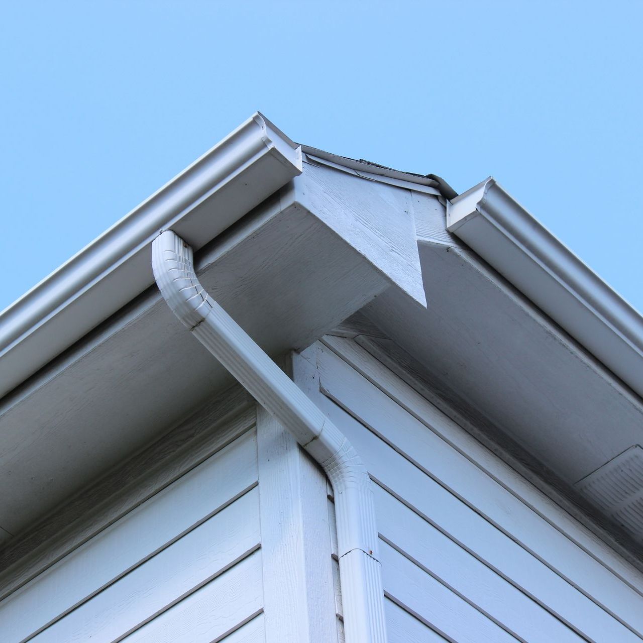 A white house with a gutter on the side of it