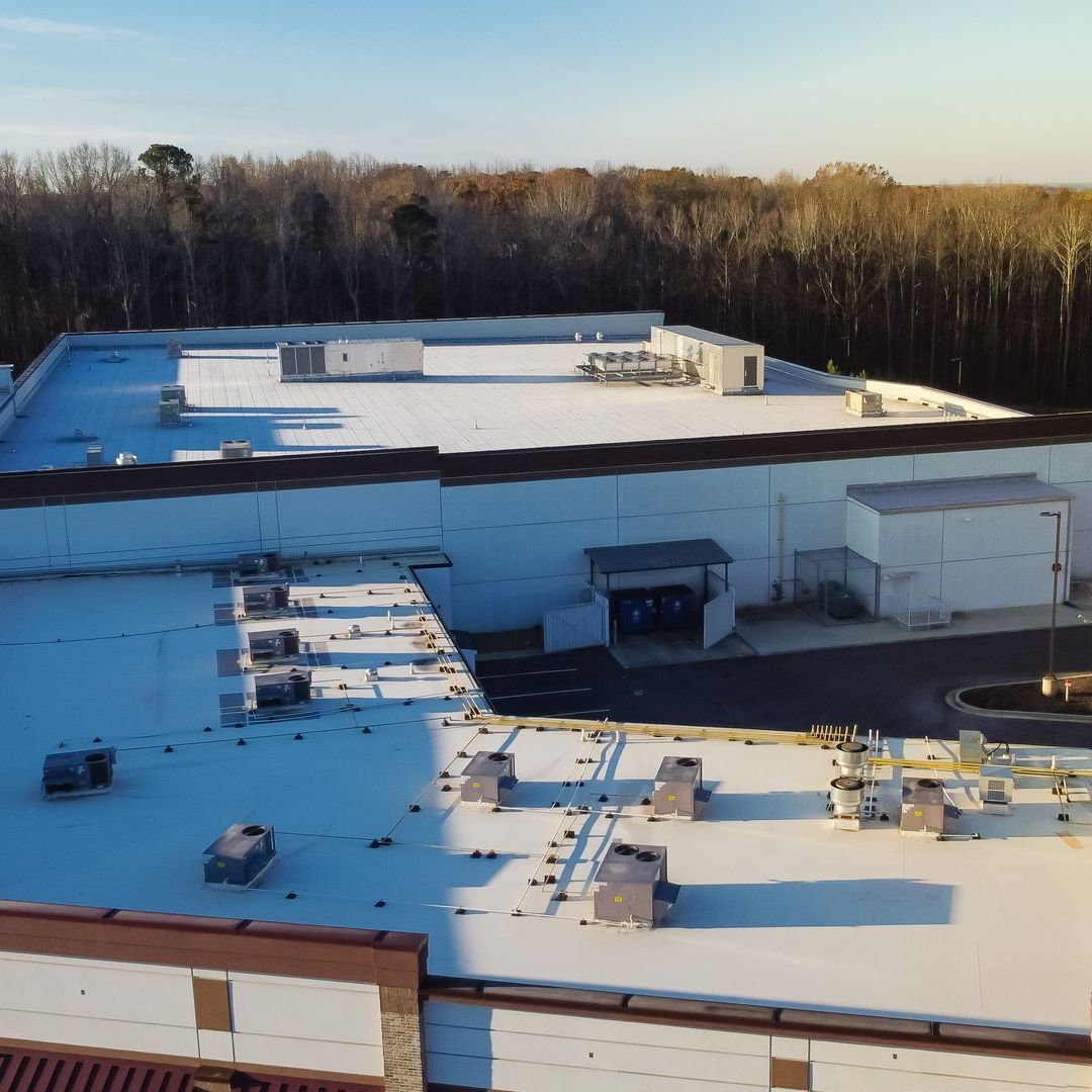 An aerial view of a large commercial  building with a white roof
